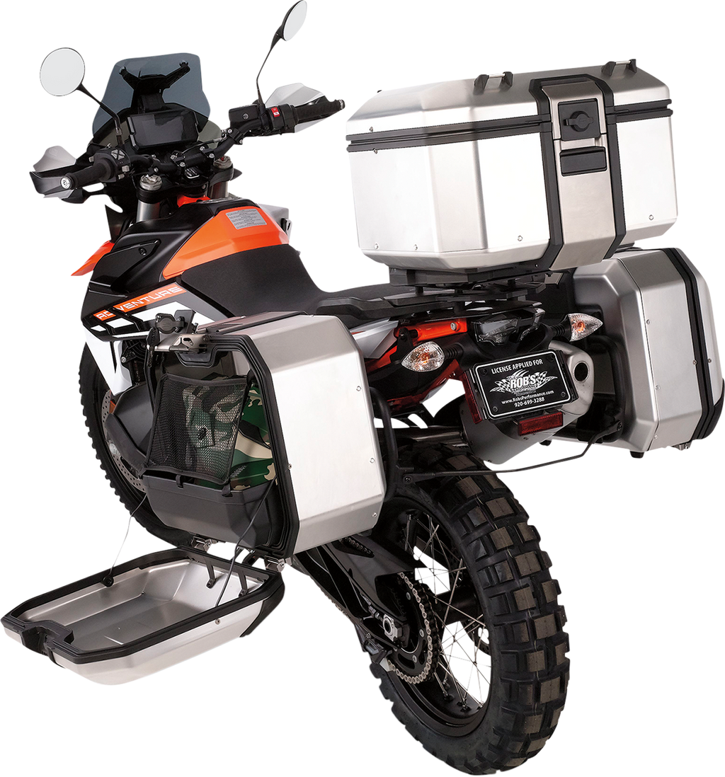 A rugged adventure motorcycle with off-road tires, black and orange body, and three large silver storage boxes—one on each side and one at the rear. The left side box is open, showing cargo space. The motorcycle has a tall windshield and visible handlebar