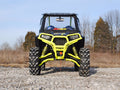 A Polaris RZR 4 900 equipped with a 3 Lift Kit features bright yellow suspension and large knobby tires, parked on rocky terrain. The windshield sports decals, while sparse trees and a clear sky appear in the background.