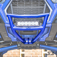 Close-up of an S3 Power Sports 2018+ Polaris Rzr Xp Turbo S Front Bumper in blue metal, with a central horizontal LED light bar. The vehicle’s grill and front end are in the background; part of a star logo is visible at the bottom right.