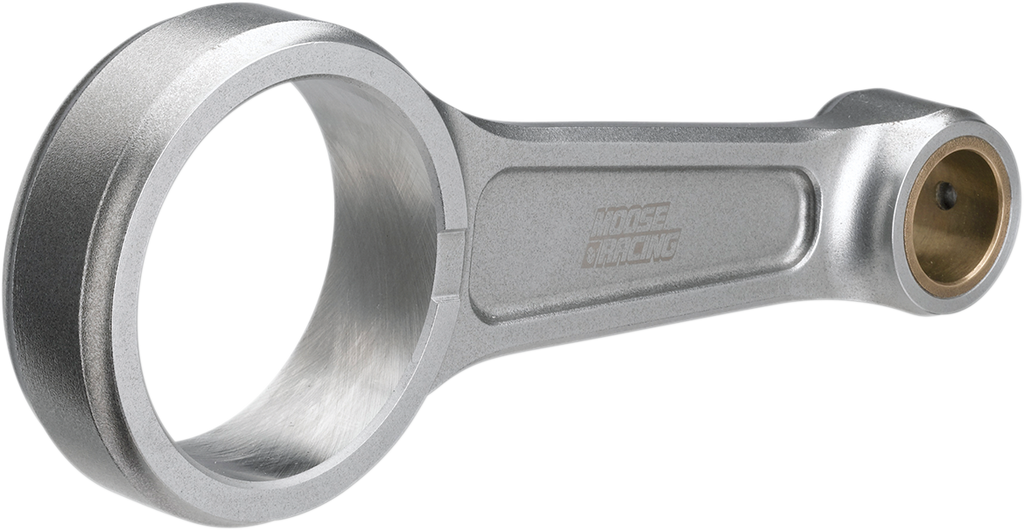 A metallic connecting rod with a brushed finish, featuring a large circular opening on one end and a smaller, bronze-bushed opening on the other. The rod has NOISE RACING engraved on its side and is set against a plain white background.