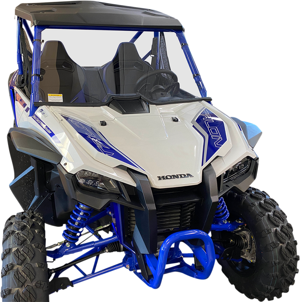 A blue and white Honda off-road utility vehicle with rugged tires, front grill, twin seats, roll cage, and suspension coils, viewed from a front angle against a plain white background.