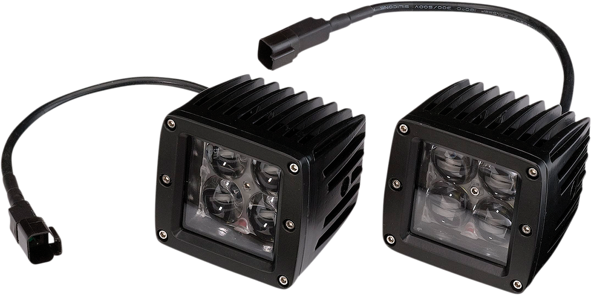 Two black, square LED off-road lights with ribbed heat sinks and clear lenses each covering four LED bulbs. Both lights have attached black power cables ending in connectors, and are positioned side by side on a white background.