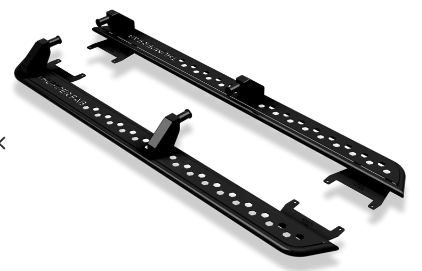 A pair of black metal 2018+ Can-Am Defender MAX Nerf Rails with evenly spaced circular holes, angular mounting brackets, and a rugged, utilitarian design ideal for off-road vehicles.