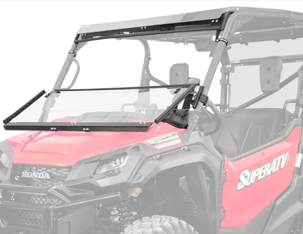 A red Honda Pioneer 1000 with “Honda” and “SuperATV” logos is shown featuring a Scratch-Resistant 3-In-1 Windshield, clear and partially open, attached by black metal brackets and hinges.