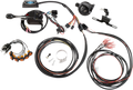 A motorcycle electronic wiring kit is laid out on a white surface. It includes various black cables, wiring harnesses, connectors, orange indicator lights, a black control box, clamps, screws, a relay, and other small electrical components.