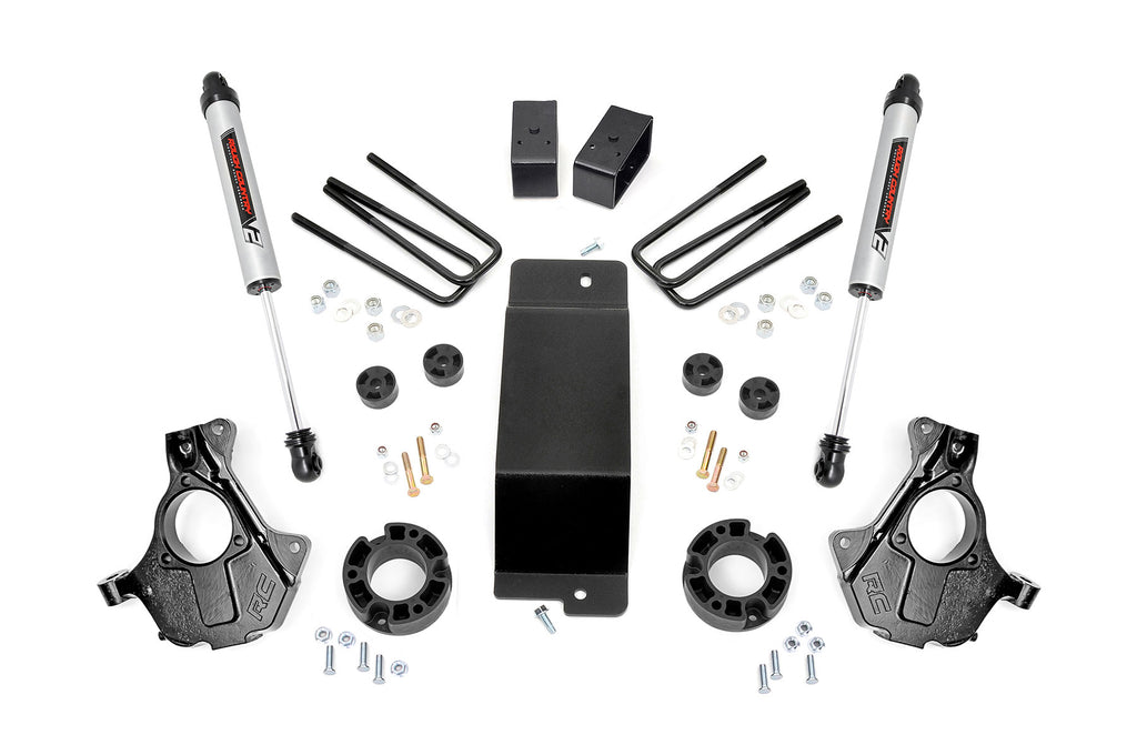 The 3.5 Inch Lift Kit | Cast Steel LCA | V2 for Chevy/GMC 1500 (14-18) is shown laid out on a white background, including shock absorbers, black knuckles, U-bolts, spacers, blocks, bolts, washers, nuts, and a central metal plate.