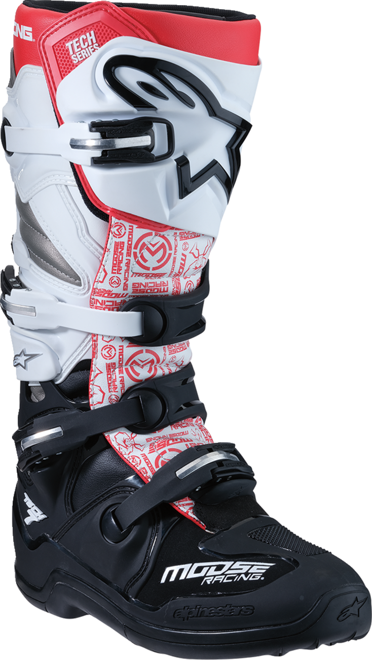 A motocross boot in black, white, and red, featuring a prominent logo of a stylized animal head on the shin guard. The boot has white and black adjustable buckles, red accents, and “MOOSE RACING” branding on the lower foot area.