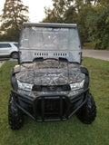A Kymco Uxv 450I with a Split Lexan Windshield (2015-2018) featuring a camouflage pattern is parked on grass near a road. Motorcycles and More, Marthasville, MO is on the windshield, with a white SUV and trees in the background.