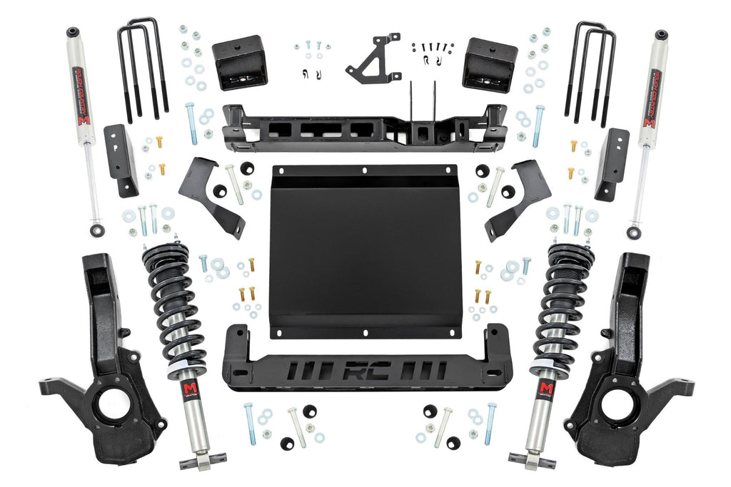 A 6 Inch Lift Kit with M1 Struts for Chevy/GMC Canyon/Colorado 4WD (2023-2024) is displayed on a white background, showing all parts—black brackets, coilovers, shocks, U-bolts, spacers—with the “RC” cutout mounting plate arranged symmetrically.