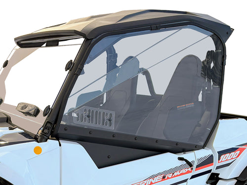 A Yamaha Wolverine X2/RMAX-2 with a tinted polycarbonate upper door kit (2021+), clear full doors and windows, black seats and roof, visible dashboard controls. The door has a vent, solid lower panel; reflective glare and power lines behind.