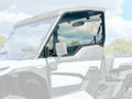A close-up of the Kawaski Ridge Tinted Polycarbonate Vented Upper Door Kit (2024+) shows the angular side mirror and tinted glass, with a blurred background of blue sky and greenery to emphasize the product.