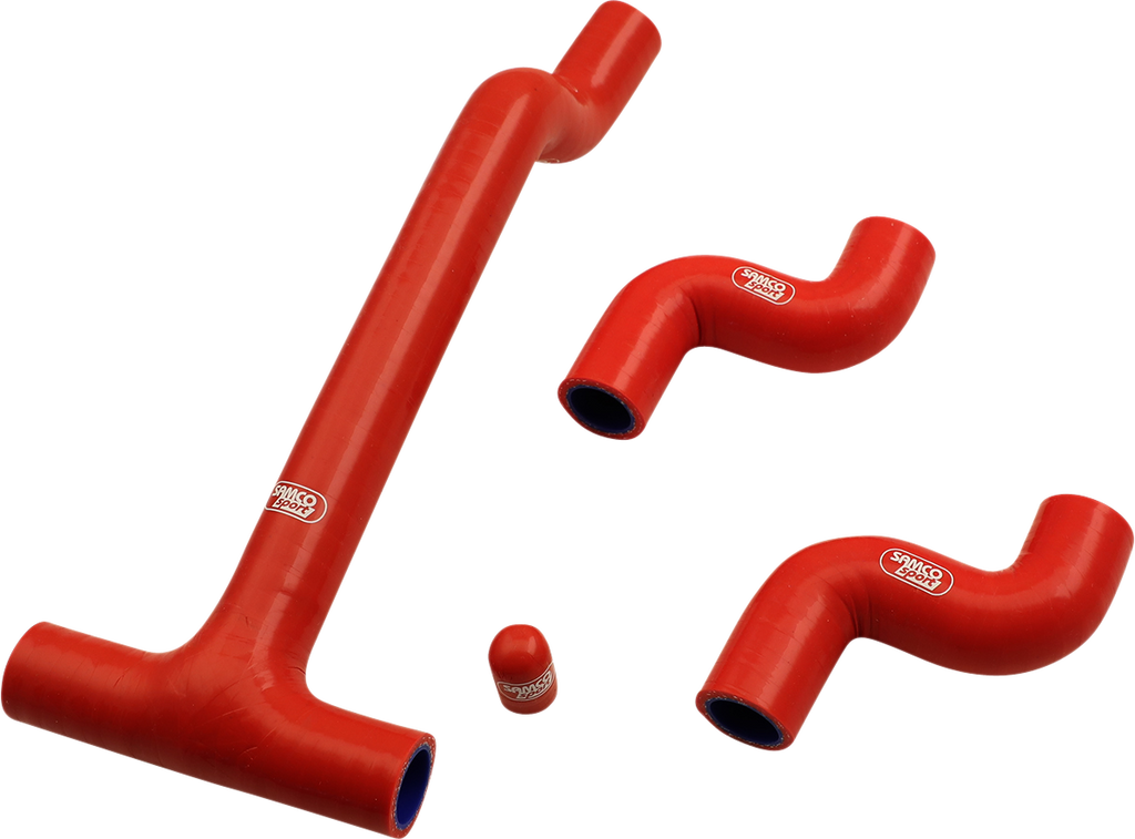 Four red silicone hoses of different shapes and sizes are arranged on a white background. Three hoses have bends and one is a small cylindrical cap. All pieces have white logos and blue interiors visible at the openings.