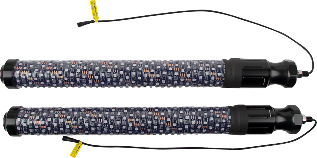 Two identical cylindrical heating rods with black end caps and patterned fabric coverings, each with a thin black power cord and yellow warning label attached, are placed parallel to each other on a white background.