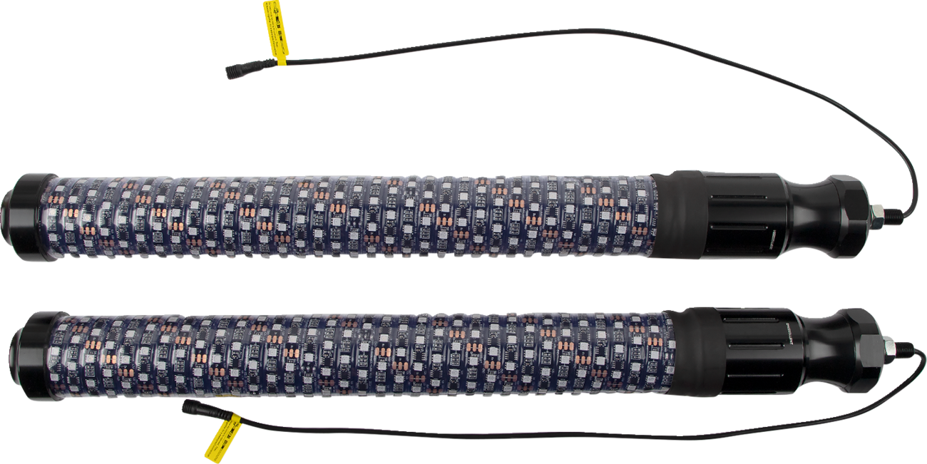 Two identical cylindrical heating rods with black end caps and patterned fabric coverings, each with a thin black power cord and yellow warning label attached, are placed parallel to each other on a white background.