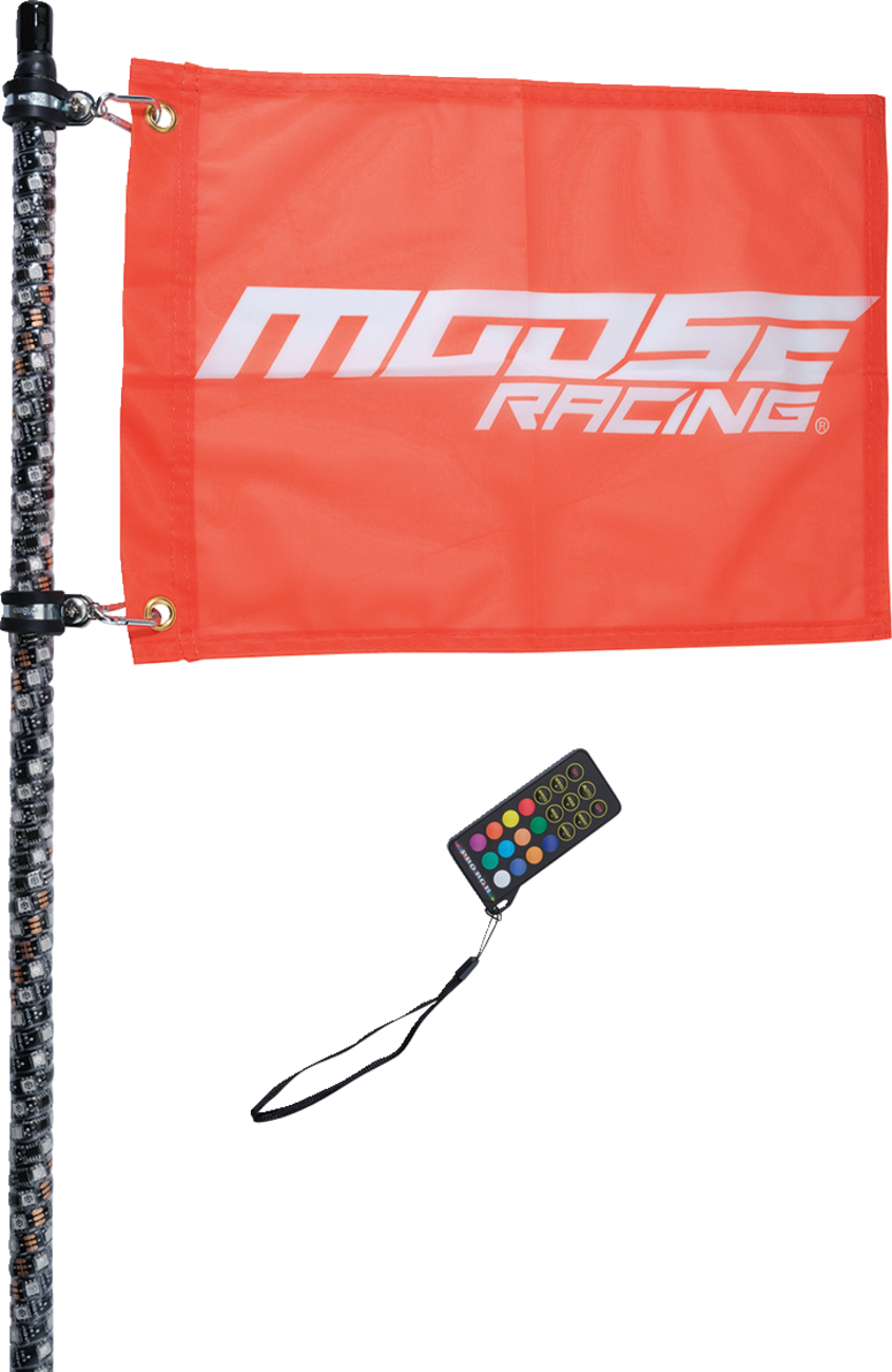 A red “Moose Racing” flag with white text is mounted on a textured black pole with LEDs. A black remote control with colorful buttons and a wrist strap is positioned below the flag. The background is plain white.