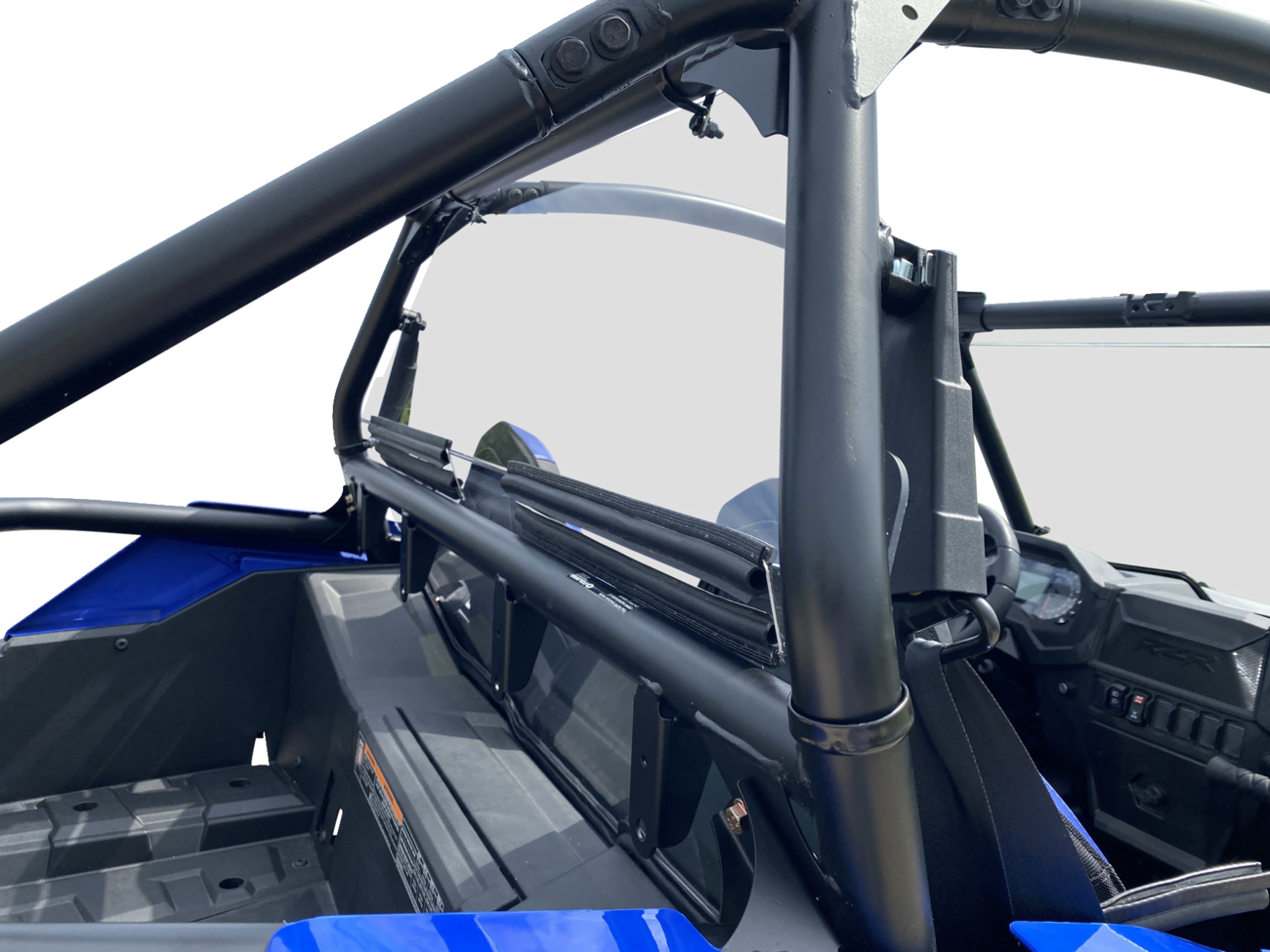 Close-up view of a blue off-road vehicle’s interior, focusing on its black tubular roll cage and safety net. The dashboard, steering wheel, seats, and rear storage compartment are visible, all under bright lighting against a white background.