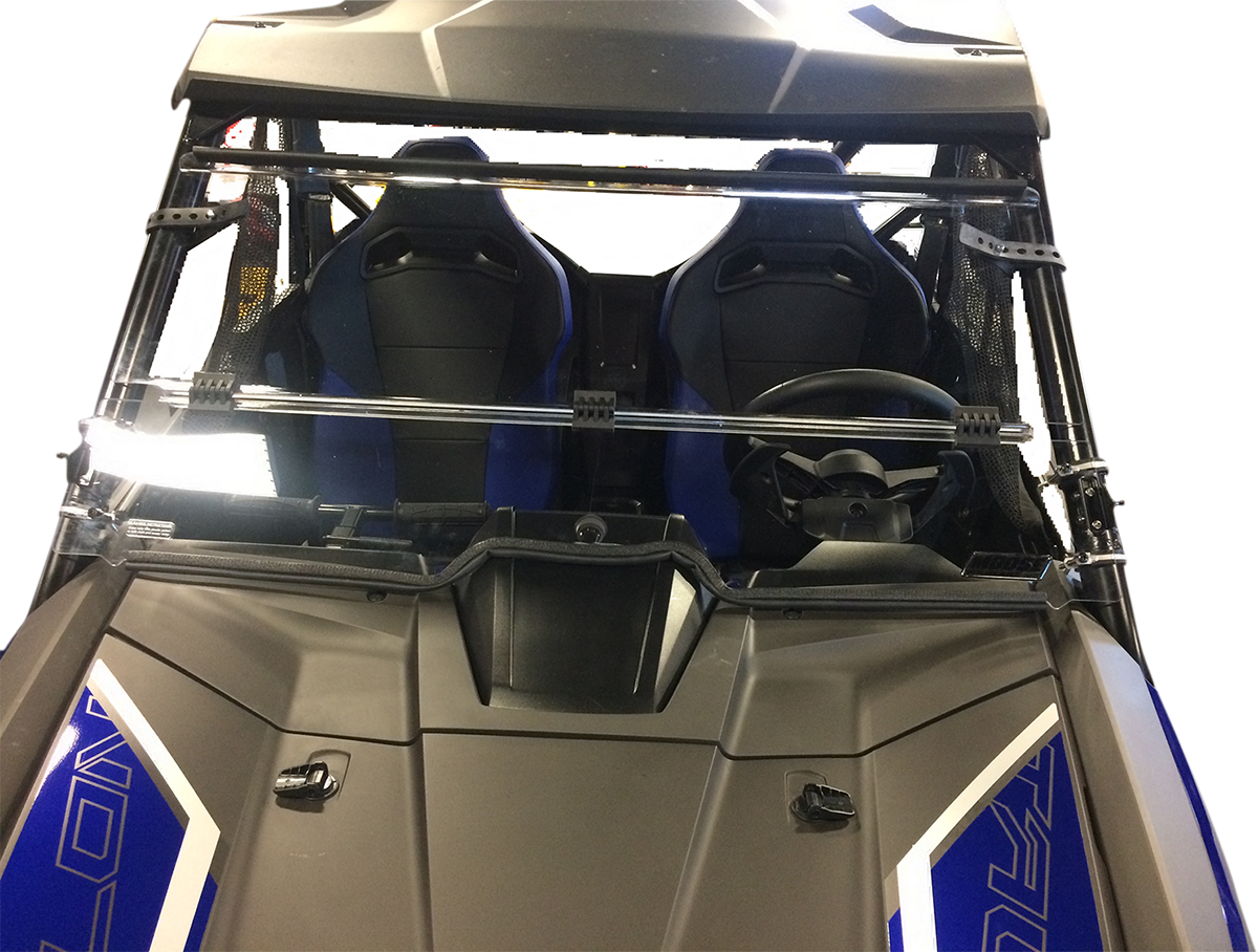 Close-up view of a vehicle’s front windshield and two blue bucket seats inside. The steering wheel is on the right, and the windshield has protective metal bars across it. The vehicle has a black and blue color scheme with angular design details.