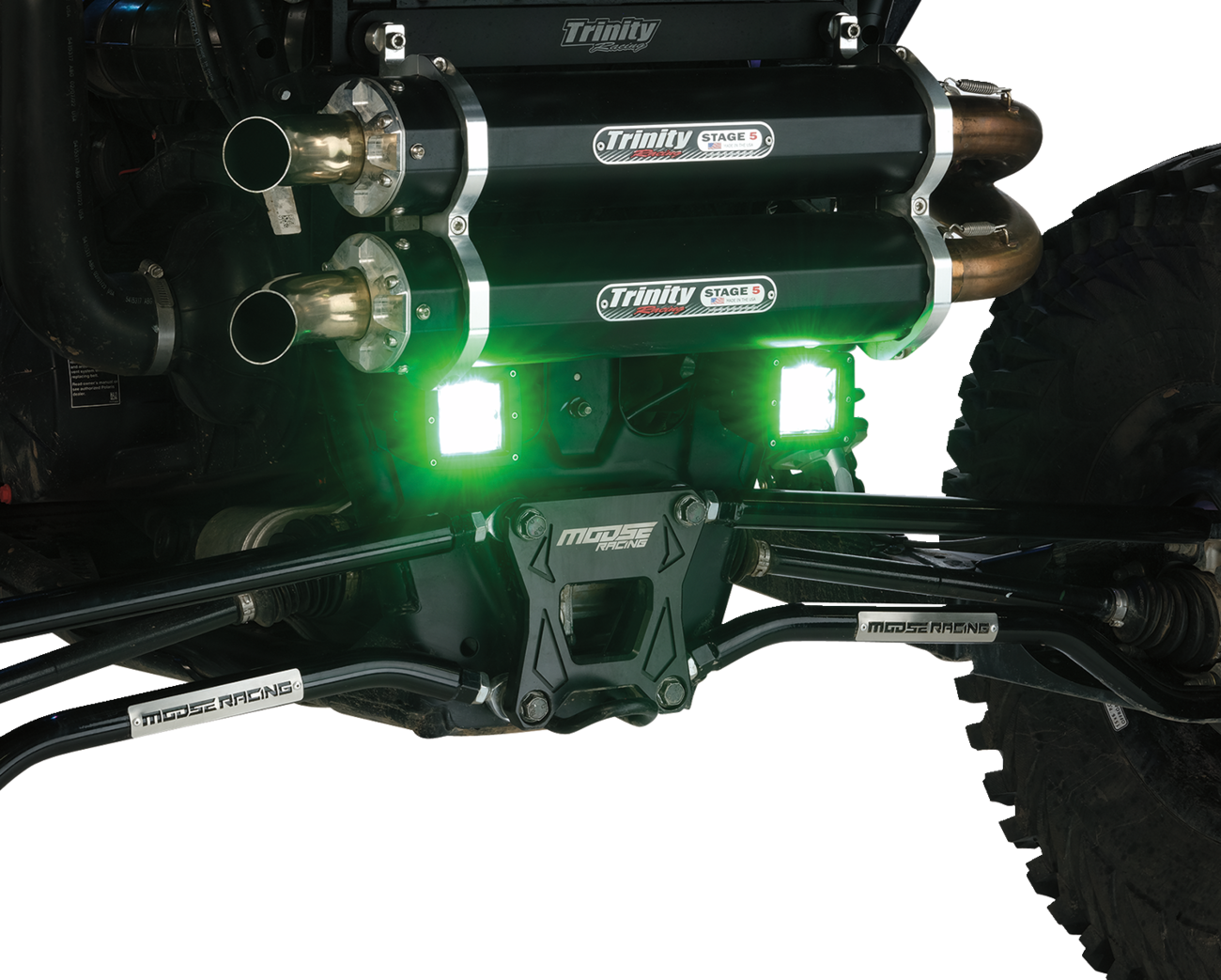 Close-up of an off-road vehicle’s rear suspension and exhaust system, featuring dual Trinity Stage 5 exhaust pipes, green LED lights, Moose Racing components, and large rugged tires, with a white background for clear detail.