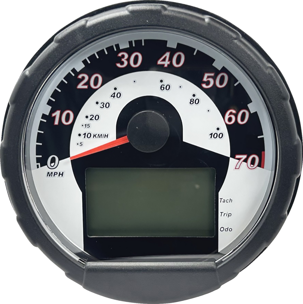 A round speedometer with a black rim and white face displays speeds from 0 to 70 MPH in red numbers. The needle points near 0. There’s a semicircular scale in KM/H and a large blank digital screen at the bottom with indicators for Tach, Trip, and Odo.