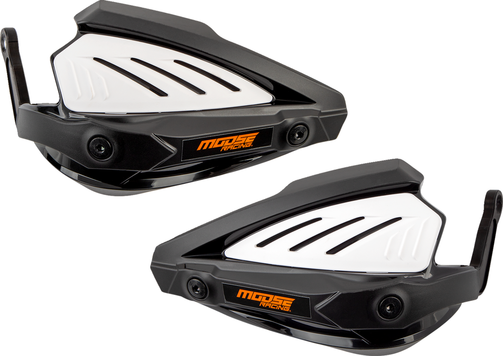 Two black and white plastic motorcycle handguards with angular designs, vented white panels, and orange Moose Racing logos are shown side by side on a light gray background. The handguards have mounting points and aerodynamic features.