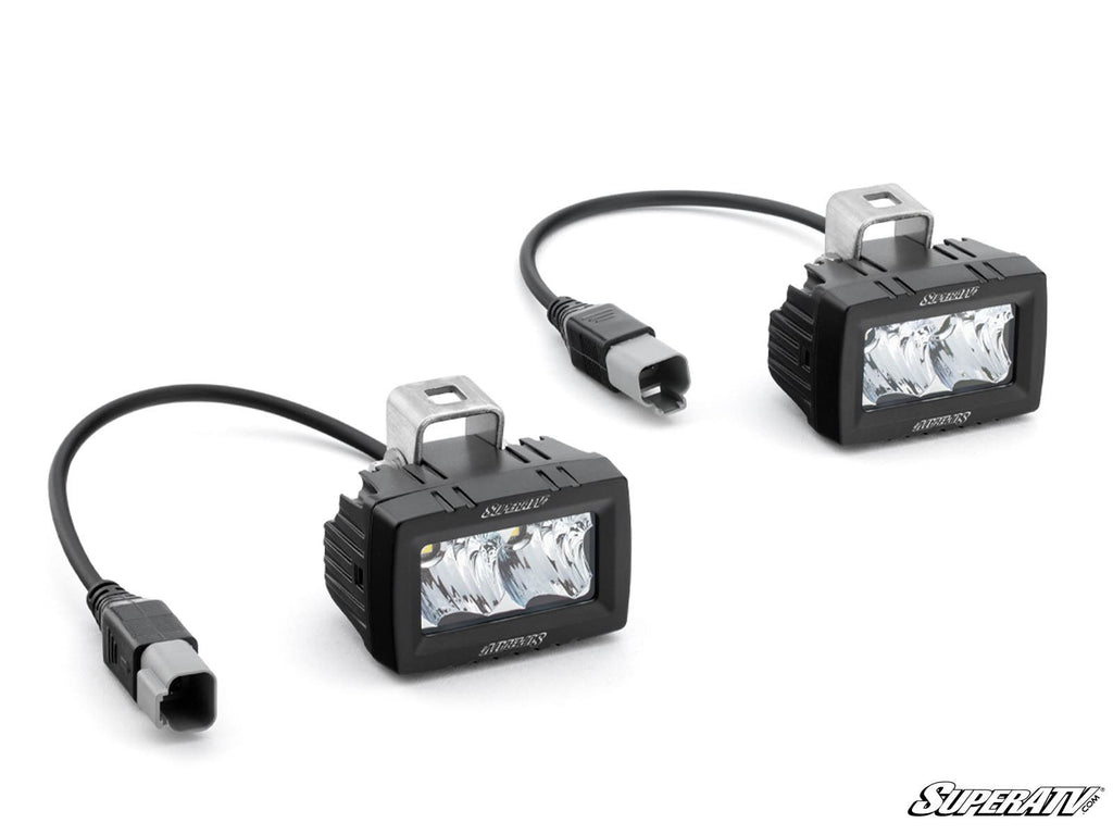 Two 3 x 1.5 Single-Row LED Cube Lights, each with metal mounting brackets and cables ending in gray connectors, are shown on a white background. SuperATV appears in the bottom right corner.