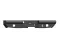 The 2003-2009 Ram 2500 Vaquero Rear Non-Winch Bumper in texture black features a rectangular center cutout, two square side cutouts, and a right-side etched logo, with smooth angular lines for a clean, modern industrial look.