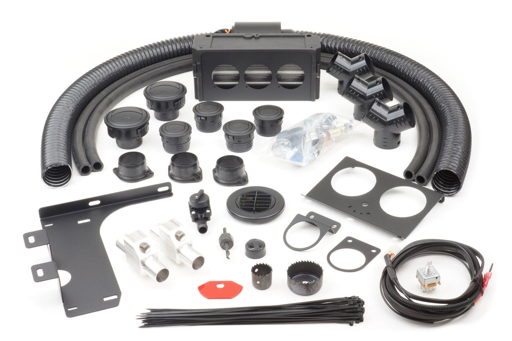 A Polaris RZR XP1000 Turbo (2016-2018) Ice Crusher Cab Heater kit is laid out on a white surface, showing black hoses, vents, brackets, connectors, wiring, zip ties, clamps, rotary vent, hole saws, screws, and a multi-port control unit.