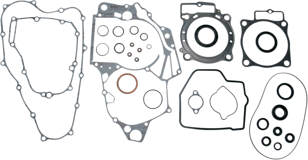 A set of various automotive engine gaskets and seals are arranged on a white background. The set includes differently shaped gaskets with multiple holes and cutouts, as well as several circular and oval seals of varying sizes.