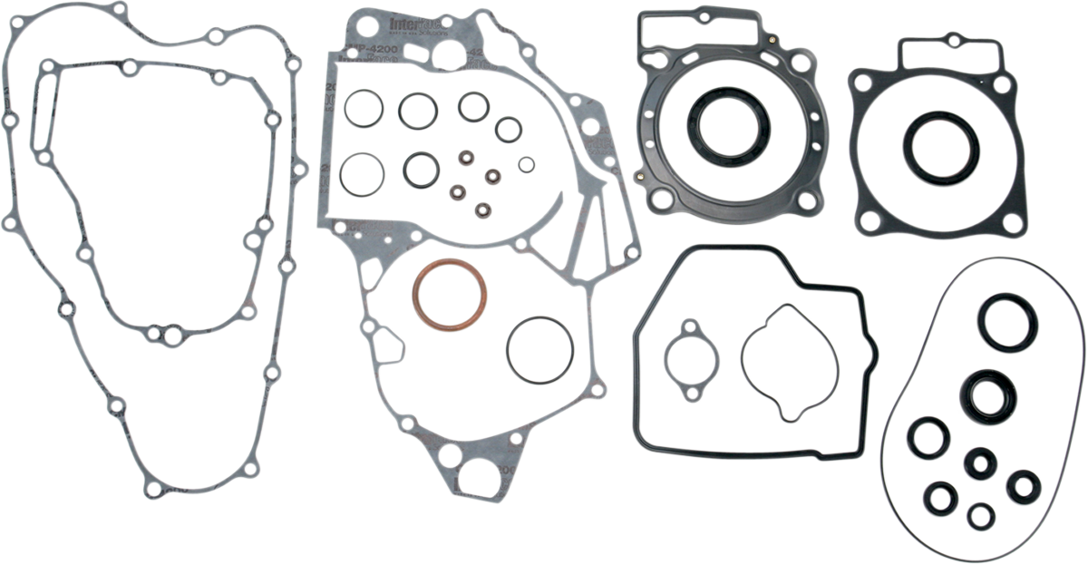 A set of various automotive engine gaskets and seals are arranged on a white background. The set includes differently shaped gaskets with multiple holes and cutouts, as well as several circular and oval seals of varying sizes.