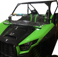 A green and black off-road utility vehicle with a partial windshield, open top, and two seats. The front features angular headlights, a black grille, and visible suspension springs beneath the hood. The background is white.