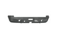 The 2003-2009 Ram 2500 Stealth Rear Winch Bumper in textured black has angular edges, accessory cutouts, and bold “ROAD ARMOR” text. The bumper fits Warn M8000 or 9.5Xp winches and is photographed on a white background.