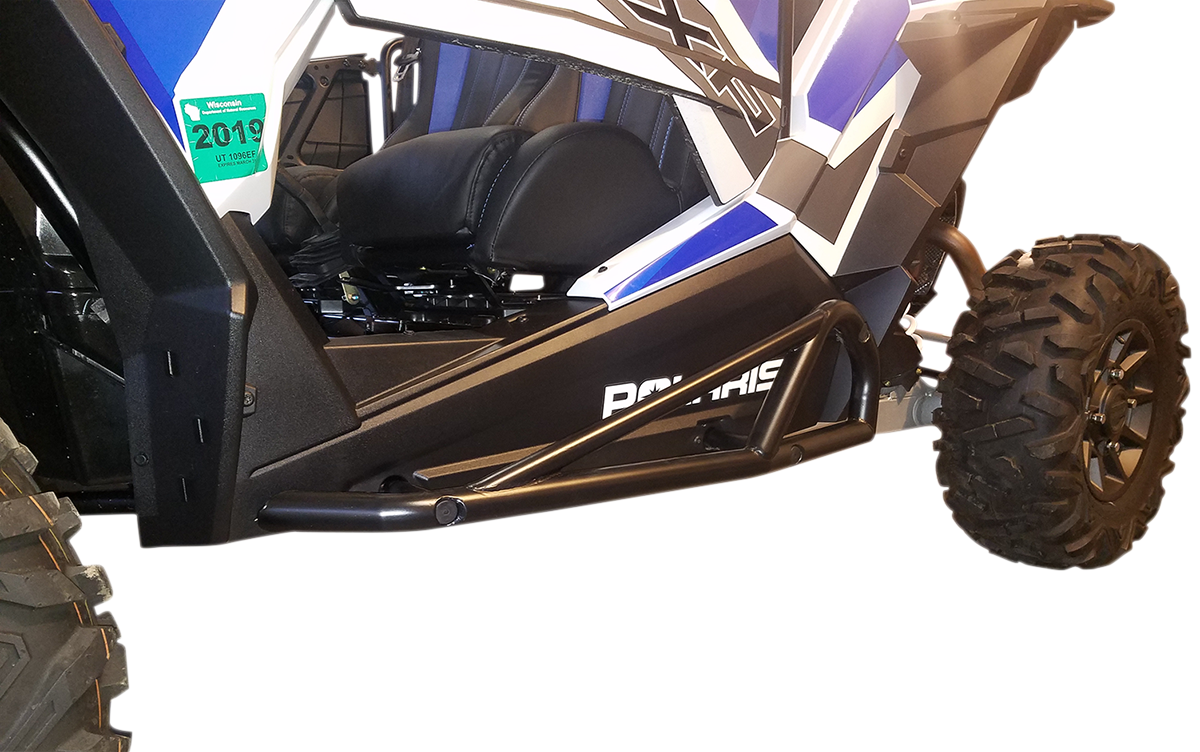Close-up view of the side of a blue and white off-road vehicle with large rugged tires, black metal side rock slider bars for protection, and the word “Polaris” visible on the side panel. A green 2019 permit sticker is also attached near the front.