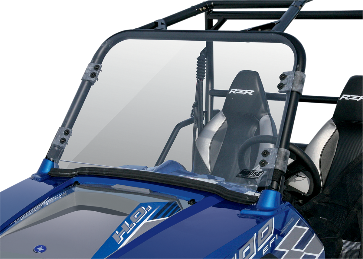 A close-up view of a blue off-road vehicle with a transparent windshield, black roll cage, and two black-and-gray bucket seats. The steering wheel and dashboard are visible, and RZR is printed on the seatbacks.