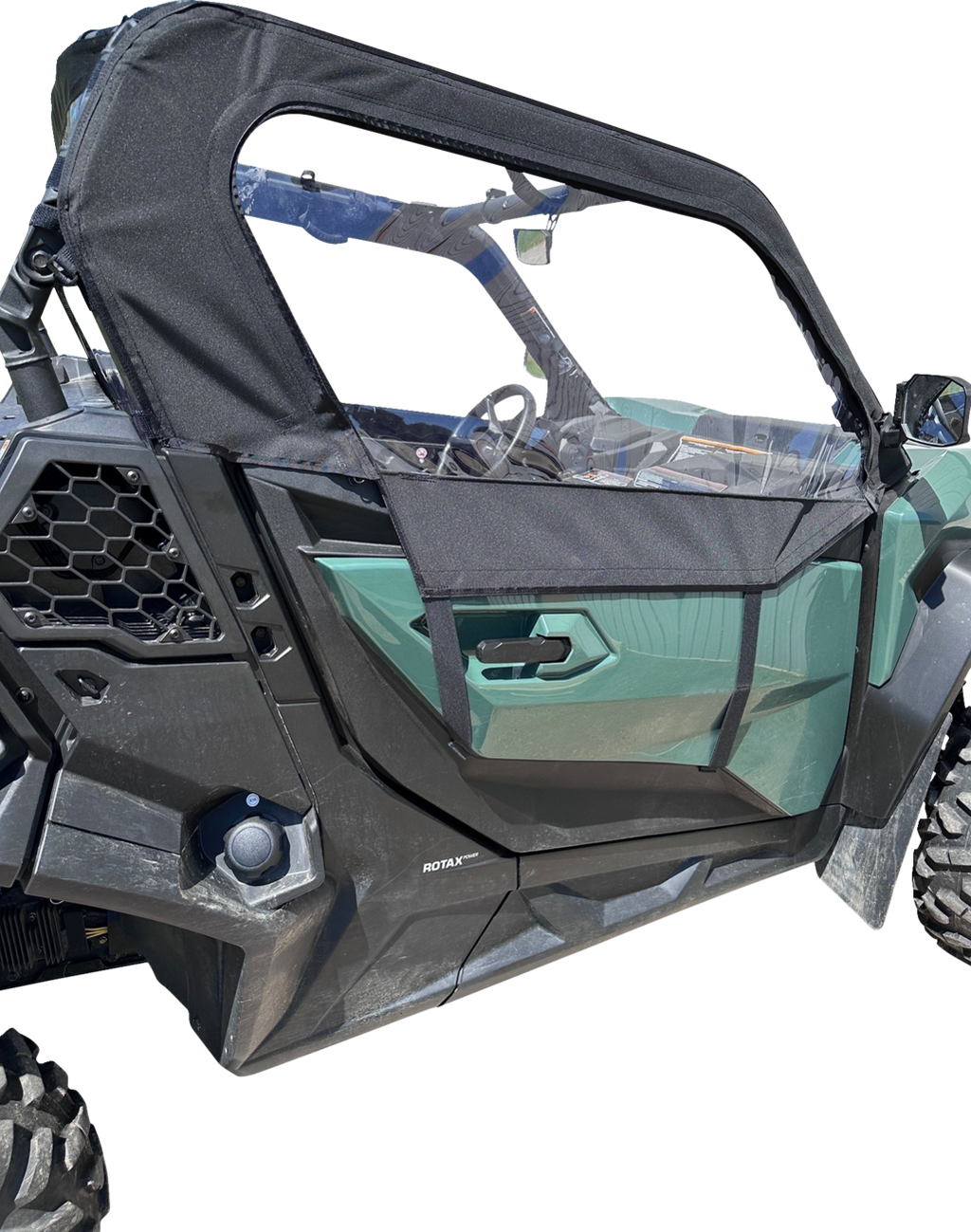 A close-up side view of a green off-road vehicle with a black mesh half-door and canopy. The door has angular lines, and the vehicle features large, rugged tires and hexagonal vent detailing near the back wheel. The interior details and steering wheel are