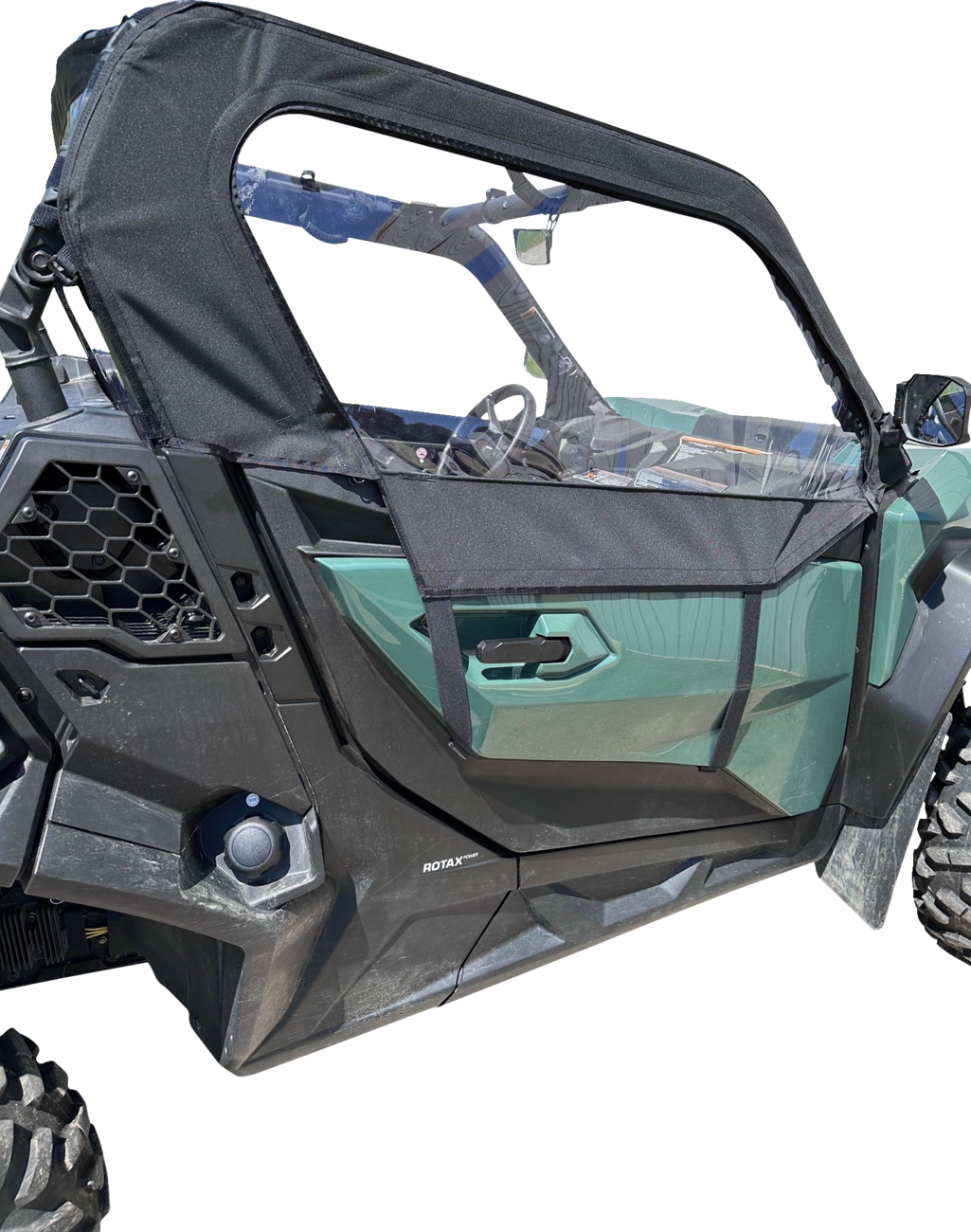 A close-up side view of a green off-road vehicle with a black mesh half-door and canopy. The door has angular lines, and the vehicle features large, rugged tires and hexagonal vent detailing near the back wheel. The interior details and steering wheel are