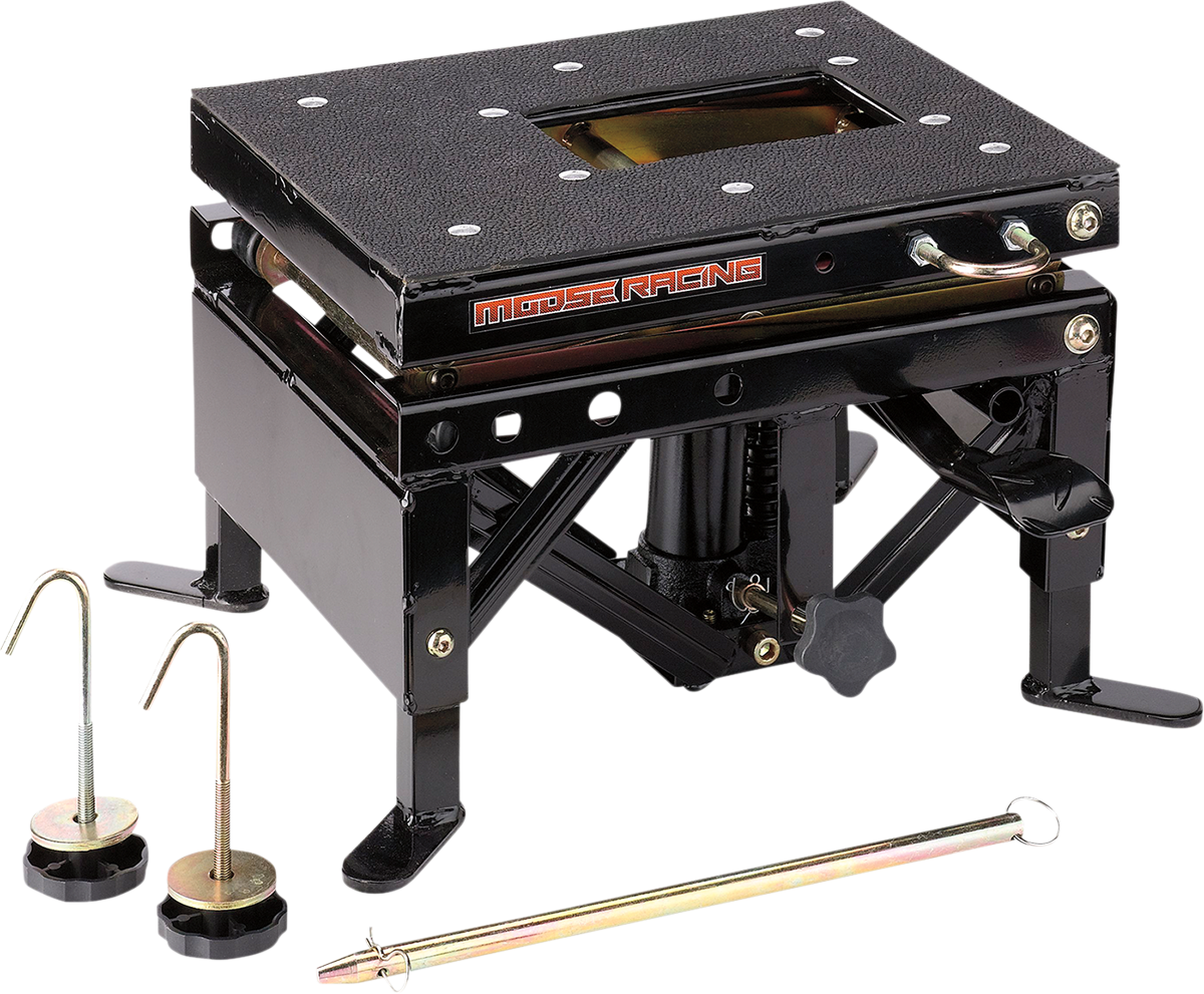 A black metal motorcycle lift table with a textured top, side crank handle, and Moose Racing logo. Two silver and black pins with hooks and a long metal rod are placed in front, all on a white background.