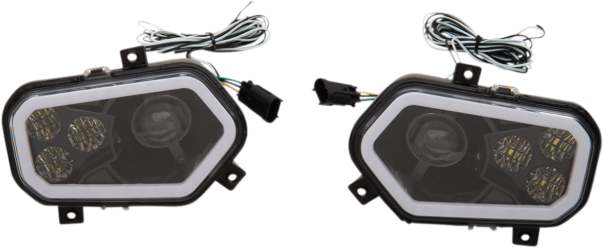 Two black, angular LED car fog lights with clear covers are shown side by side. Each light has three circular LED clusters and a larger single lens inside, with attached wiring and black connectors extending from the top. The lights rest on a white backgr