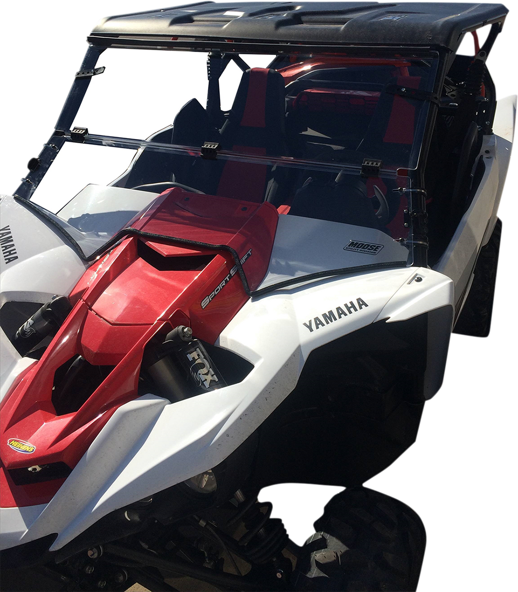 A white and red Yamaha off-road side-by-side vehicle with a roof, open sides, heavy-duty tires, FOX shocks, and bold Yamaha logos on the hood and fenders; two bucket seats are visible through the windshield.