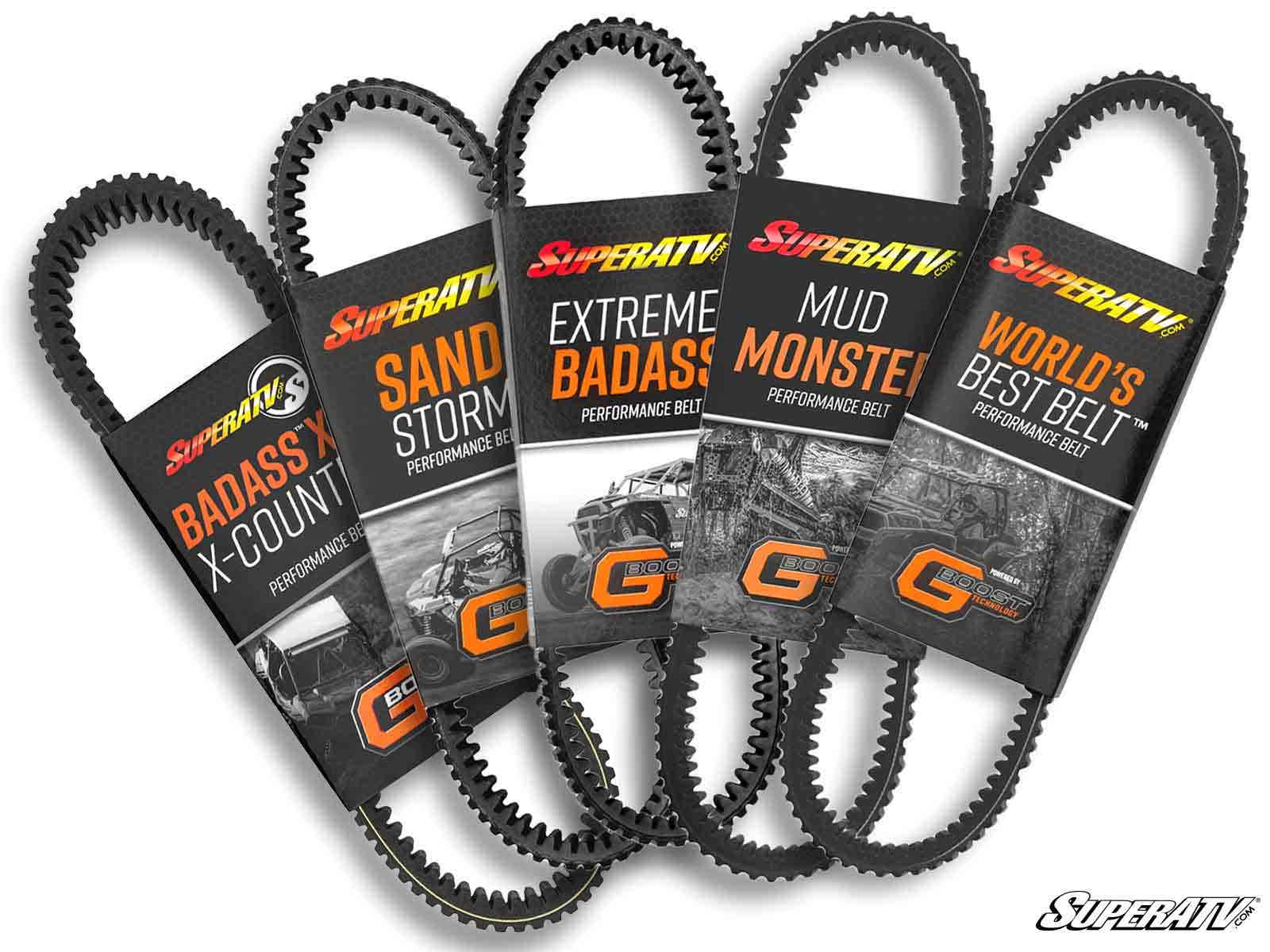 Five Polaris Xpedition Heavy-Duty CVT Drive Belts stand upright in a row, each with a colorful label: BADASS X–K-COUNT, SAND STORM, EXTREME BADASS, MUD MONSTER, and WORLD’S BEST BELT. The SuperATV logo is at bottom right.