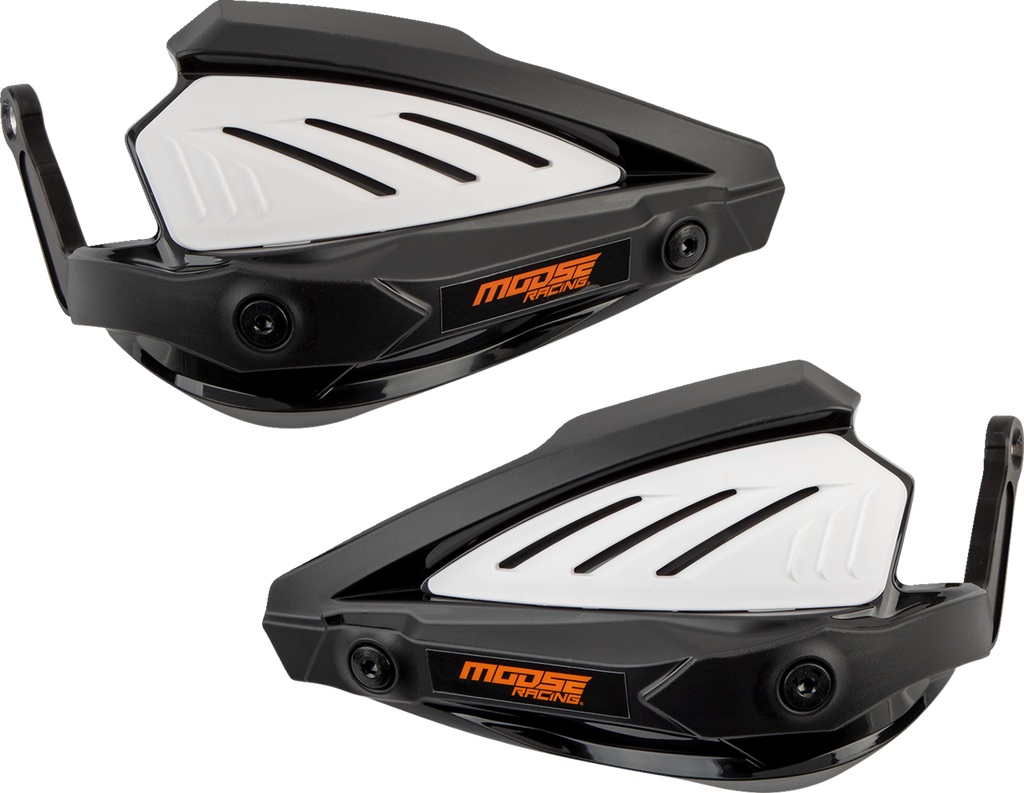 Two black and white plastic handguards with vented panels and the “Moose Racing” logo in orange on each guard. They feature a angular design with mounting hardware visible on one end of each guard. Both handguards are positioned side by side with a light 