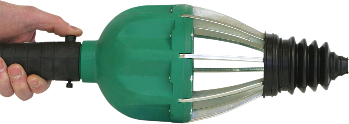 A hand grips the black handle of a green and silver mechanical tool with metal prongs and a black, ridged rubber cone at the end. The tool appears to be a pipe or drain cleaning device, held horizontally against a white background.