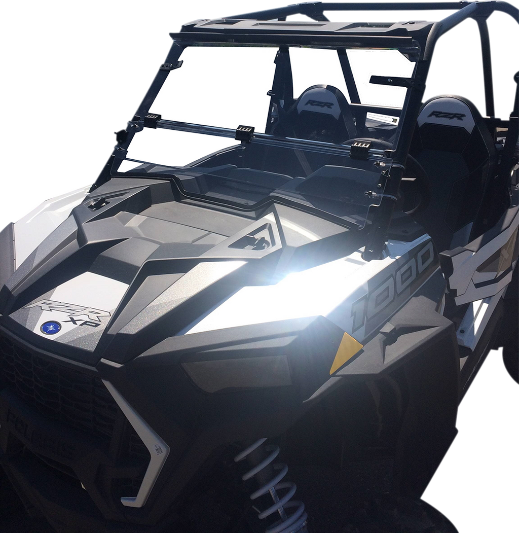 A black off-road utility vehicle with angular, rugged design, roll cage, two visible seats labeled “RZR,” and “1000” marking on the side. The windshield is partially open, and the sunlight reflects brightly off the vehicle’s front panel.