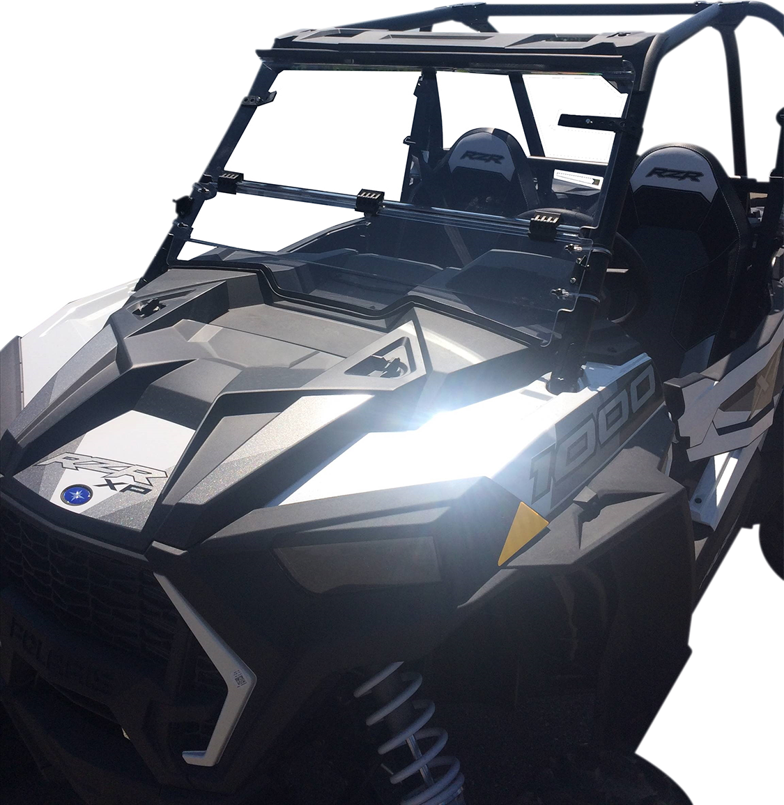 A black off-road utility vehicle with angular, rugged design, roll cage, two visible seats labeled “RZR,” and “1000” marking on the side. The windshield is partially open, and the sunlight reflects brightly off the vehicle’s front panel.