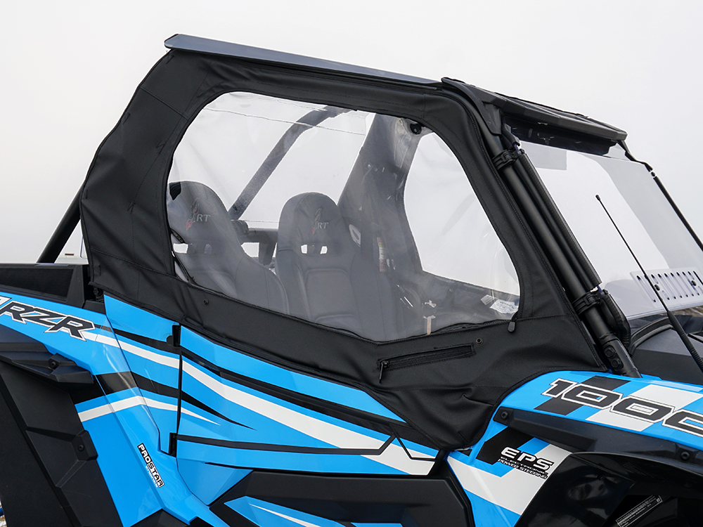 A close-up side view of a Polaris Rzr 900/1000 with the Spike Framed Upper Door Kit, showing blue body, black and white accents, two bucket seats, clear plastic windows, zippered fabric door, visible roll cage, and partial windshield.