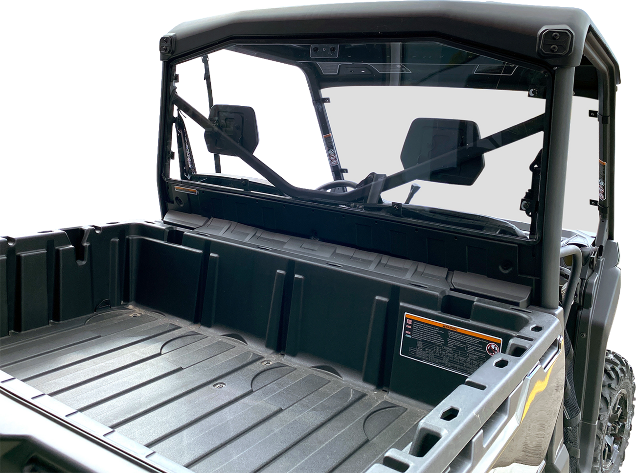 Close-up view of the empty rear cargo bed of a black utility task vehicle (UTV). The image shows the rear window, roll cage, and interior seats through the glass, with warning labels visible on the side of the cargo bed.