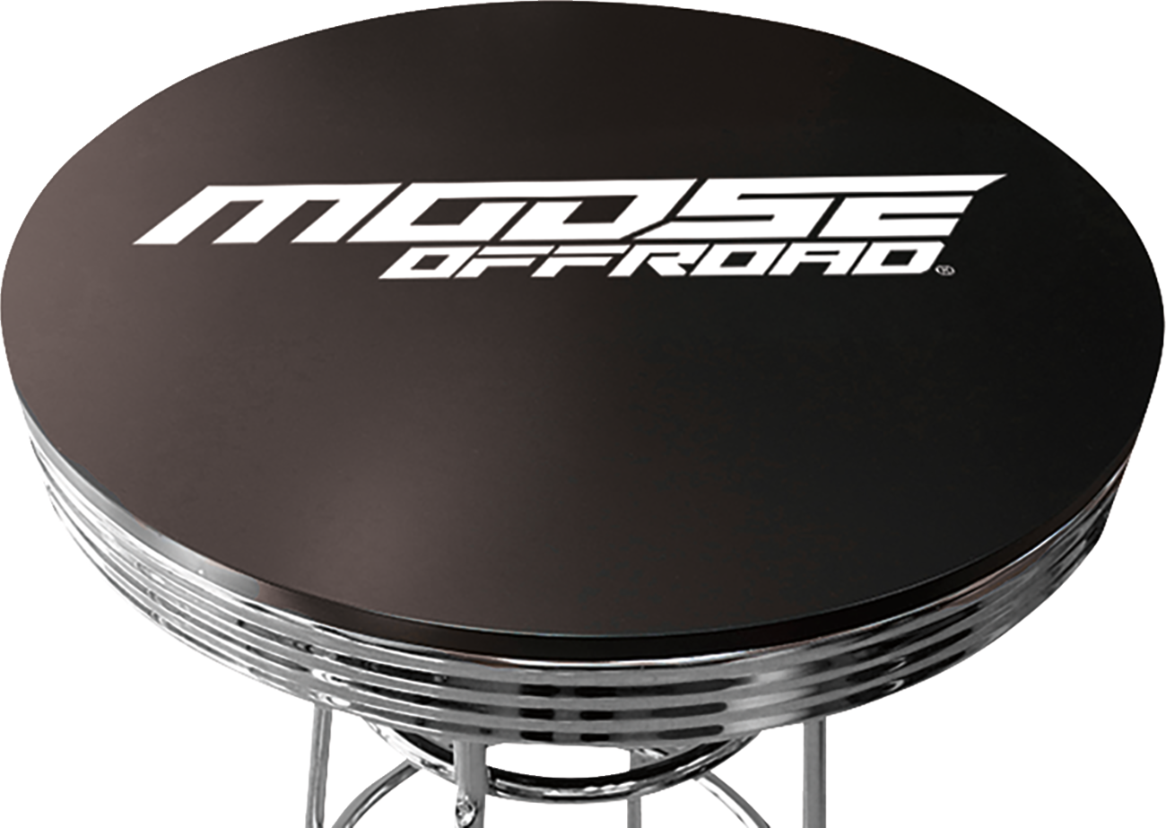 A round, black tabletop with the words MOOSE OFFROAD in bold, white, stylized letters across the surface. The tabletop has a shiny, chrome edge and is supported by metal legs.
