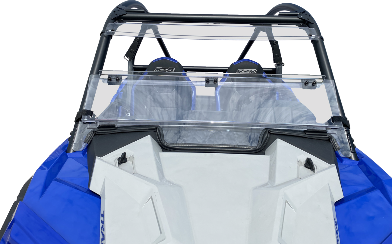 A close-up view of the front interior of a blue and white off-road vehicle, featuring two black seats with RZR logos and a transparent windshield attached to a black roll cage. The vehicles angular hood and side panels are also visible.