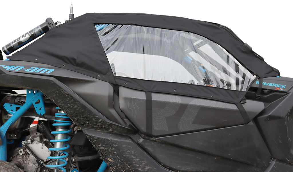 A black soft cab enclosure with a clear plastic window covers the side of a blue Can-Am Maverick X3 off-road vehicle, protecting the interior while still showing the suspension and mud on the lower panels.