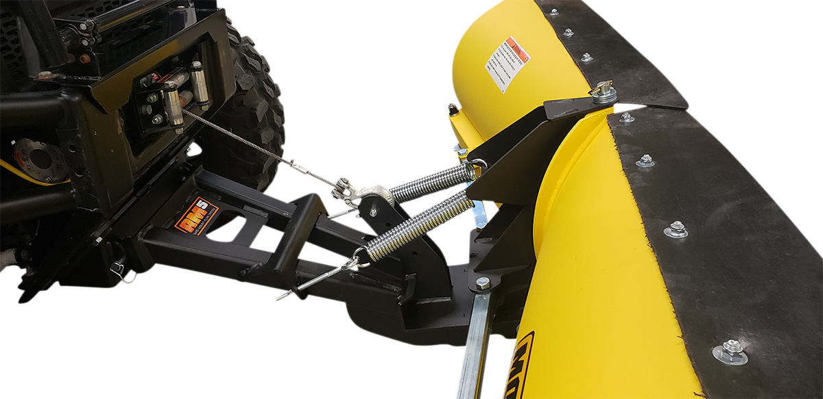 Close-up of a yellow snow plow blade attached to the front of a vehicle. The plow is secured with metal springs and bolts, and features a black mounting bracket. The setup is designed for clearing snow, with visible mechanical connection details.
