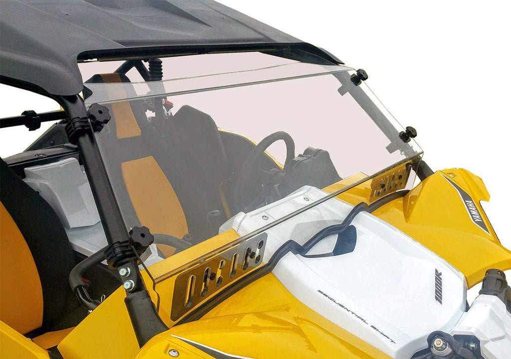 A close-up of a Yamaha YXZ (2016-2018) with a Full Hard Coated Windshield featuring dual sliding vents, mounted with black clamps. The clear windshield reveals the sporty cab interior, steering wheel, and angular yellow body panels.